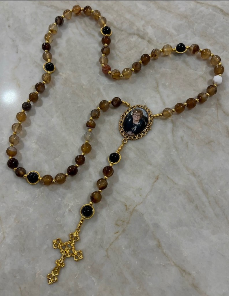 Brown agate rosary with black accent beads, a custom photo in the center, and an ornate gold cross.