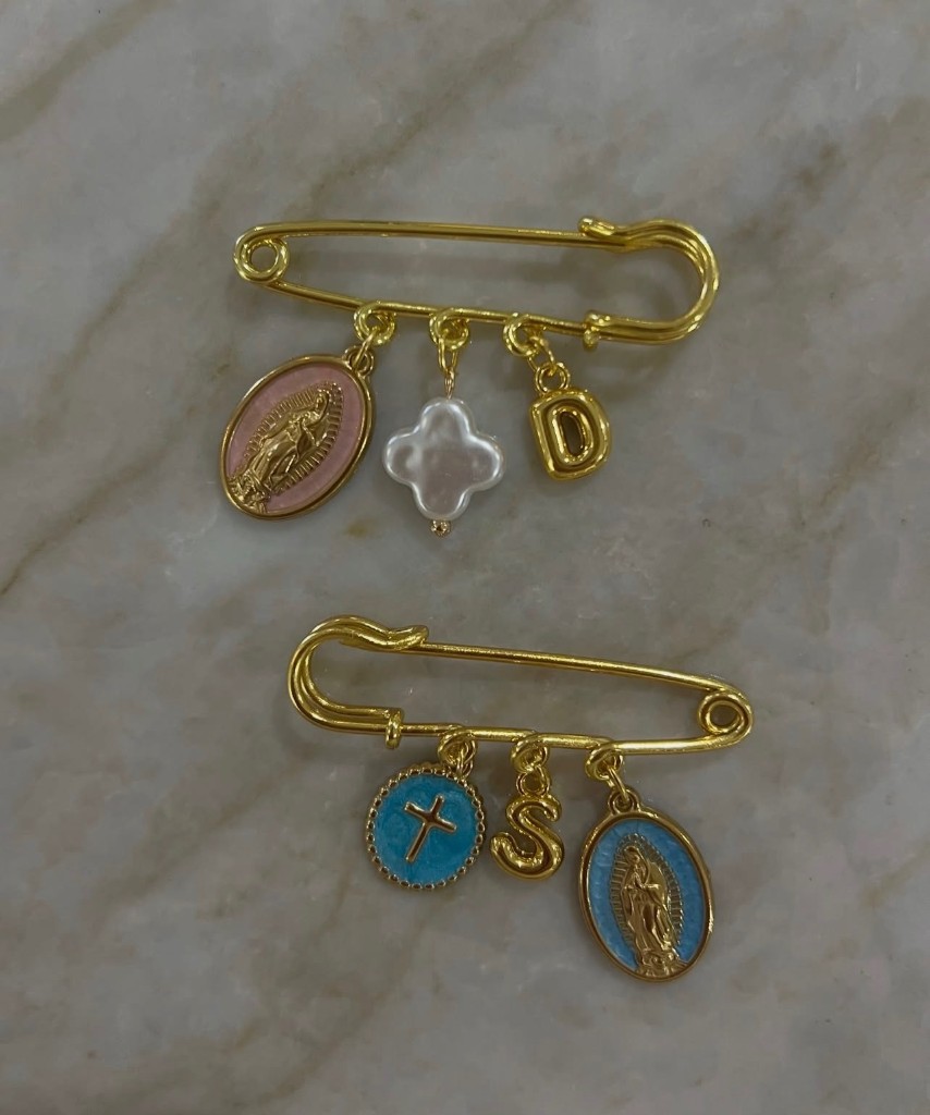 Two gold 3-charm baby pins with Our Lady of Guadalupe medals and letter charms.