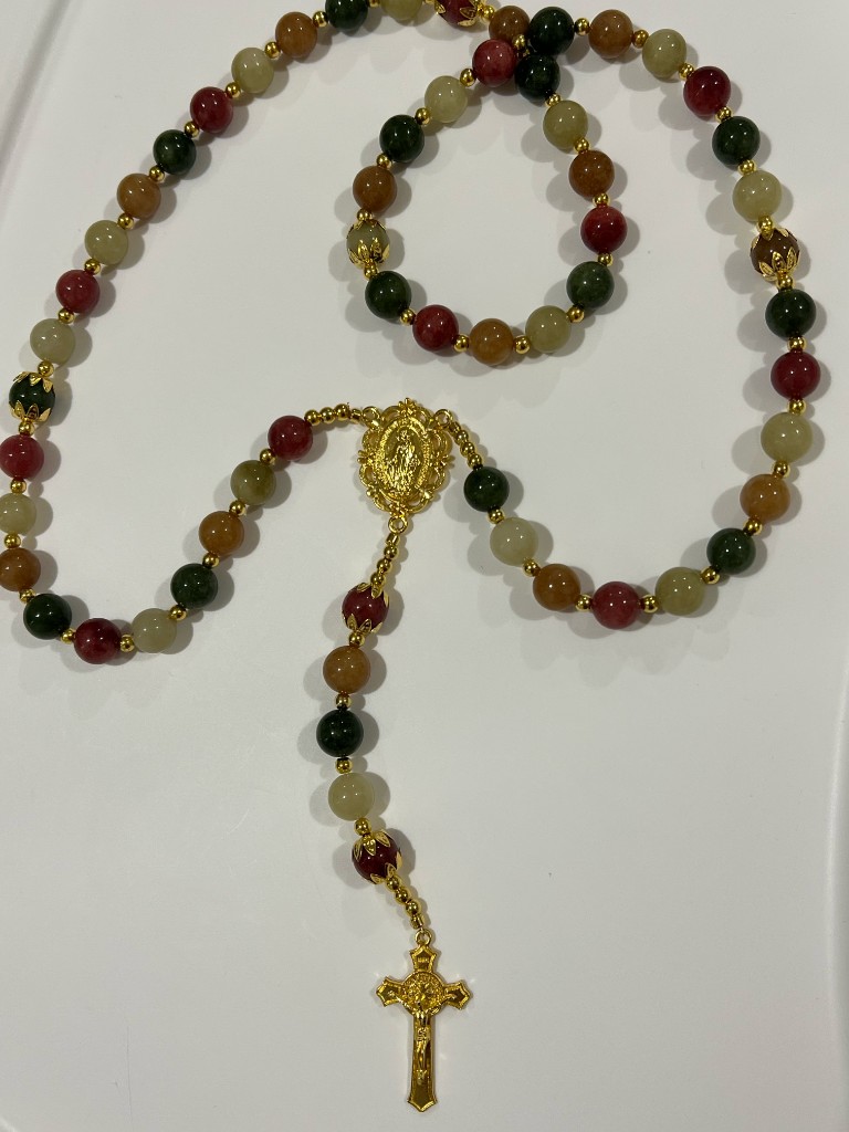 Mixed green, red, and gold bead rosary with a gold Miraculous Medal and a gold crucifix.