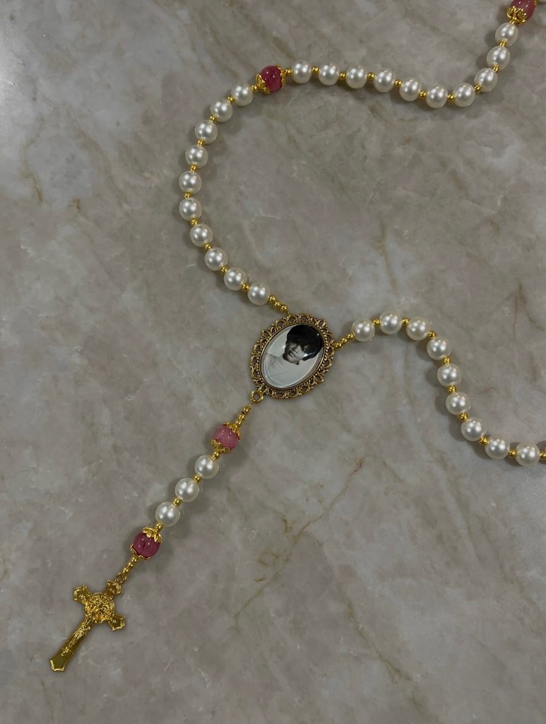 Ivory pearl rosary with pink accent beads, a custom photo in the center, and a gold crucifix.