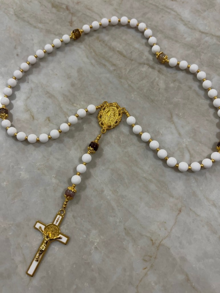 White round-bead rosary with gold spacers, a gold center medal, and a white enamel crucifix.